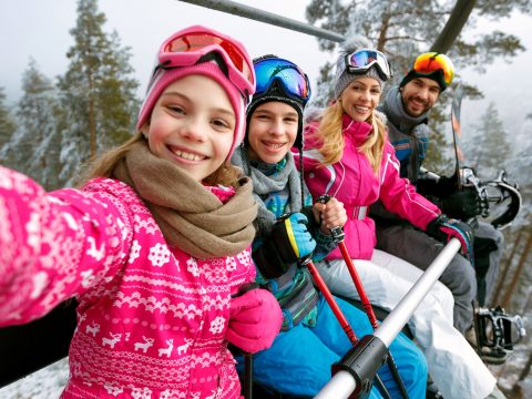 Family Taking Selfie on Ski Lift; Courtesy of Lucky Business/Shutterstock.com