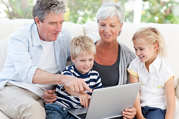 Grandparents and grandkids crowded around a laptop.