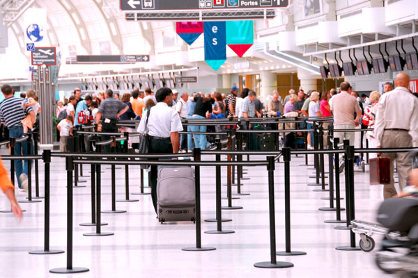 Passengers lining up at airport check-in counter.
