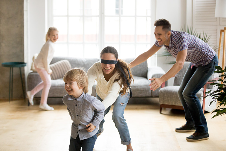 Blindfolded mother catching little son playing hide and seek at home; Courtesy of fizkes/Shutterstock