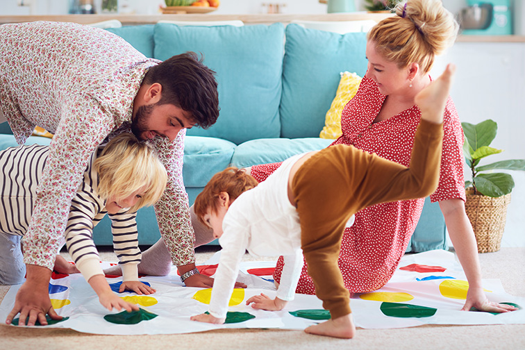 family having fun together, playing twister game at home; Courtesy of Olesia Bilkei/Shutterstock