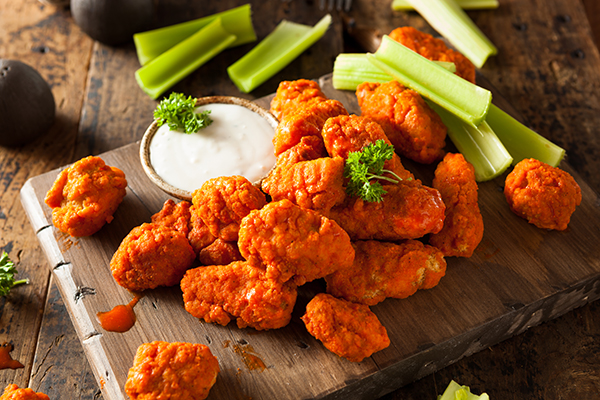 Original Buffalo wings paired with celery and glistening with sauce.
