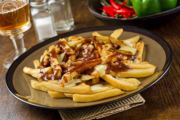 When in Canada, don't miss the chance to try their famous French-fry-based dish of poutine; Courtesy of Foodio/Shutterstock.com Poutine is one of Canada's most famous foods, with French fries, cheese curds, and gravy.