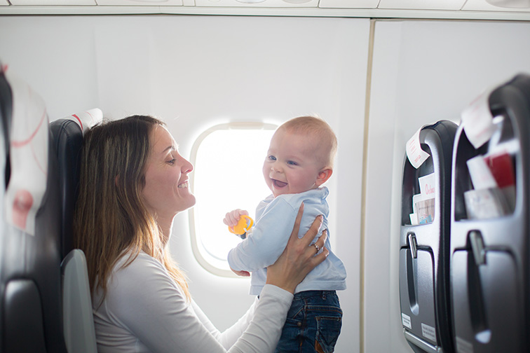 Young mom, playing and breastfeeding her toddler boy on board of aircraft; Courtesy of Tomsickova Tatyana/Shutterstock