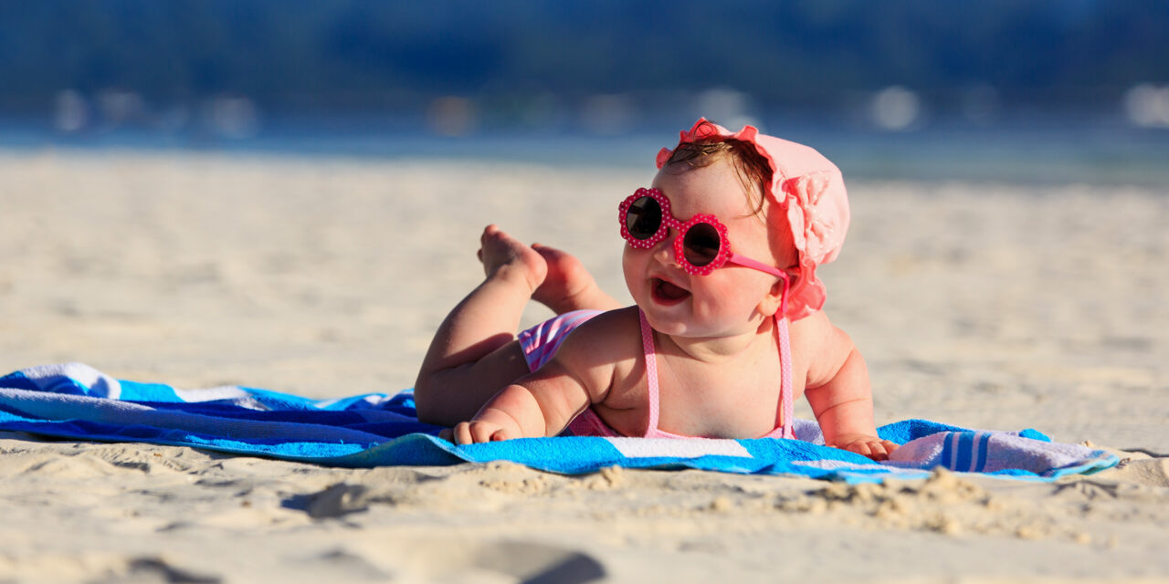 cute little baby girl on tropical sand beach ; Courtesy of NadyaEugene/Shutterstock