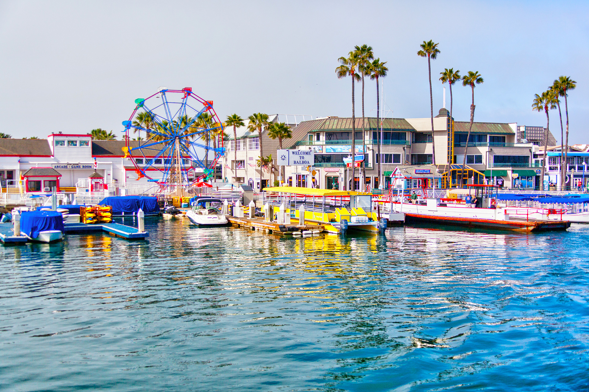 Popular pier at Balboa peninsula in Southern California with ferris wheel, tourist shops, restaurants and boats doting the harbor ferry terminal.; Courtesy of Ronnie Chua/Shutterstock