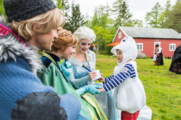 Anna, Elsa and Kristoff sign autographs for a little boy dressed as Olaf the snowman.