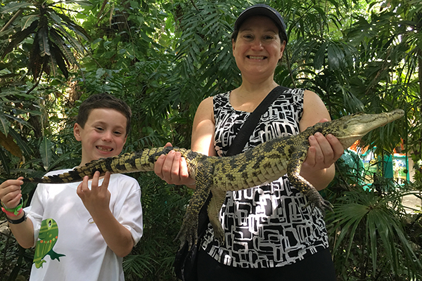 Mother and son holding a crocodile.