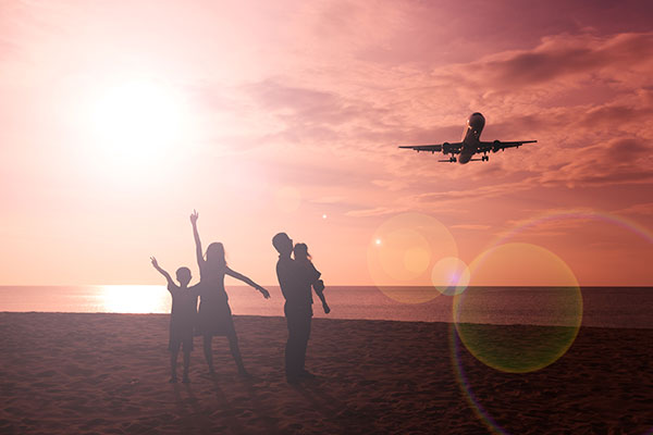 Family watching a plane fly overhead from the beach.