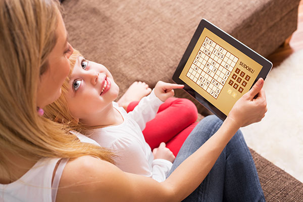 A mother and child playing a game on an iPad.