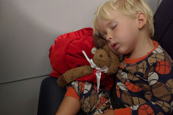 A little boy sleeping on a plane.