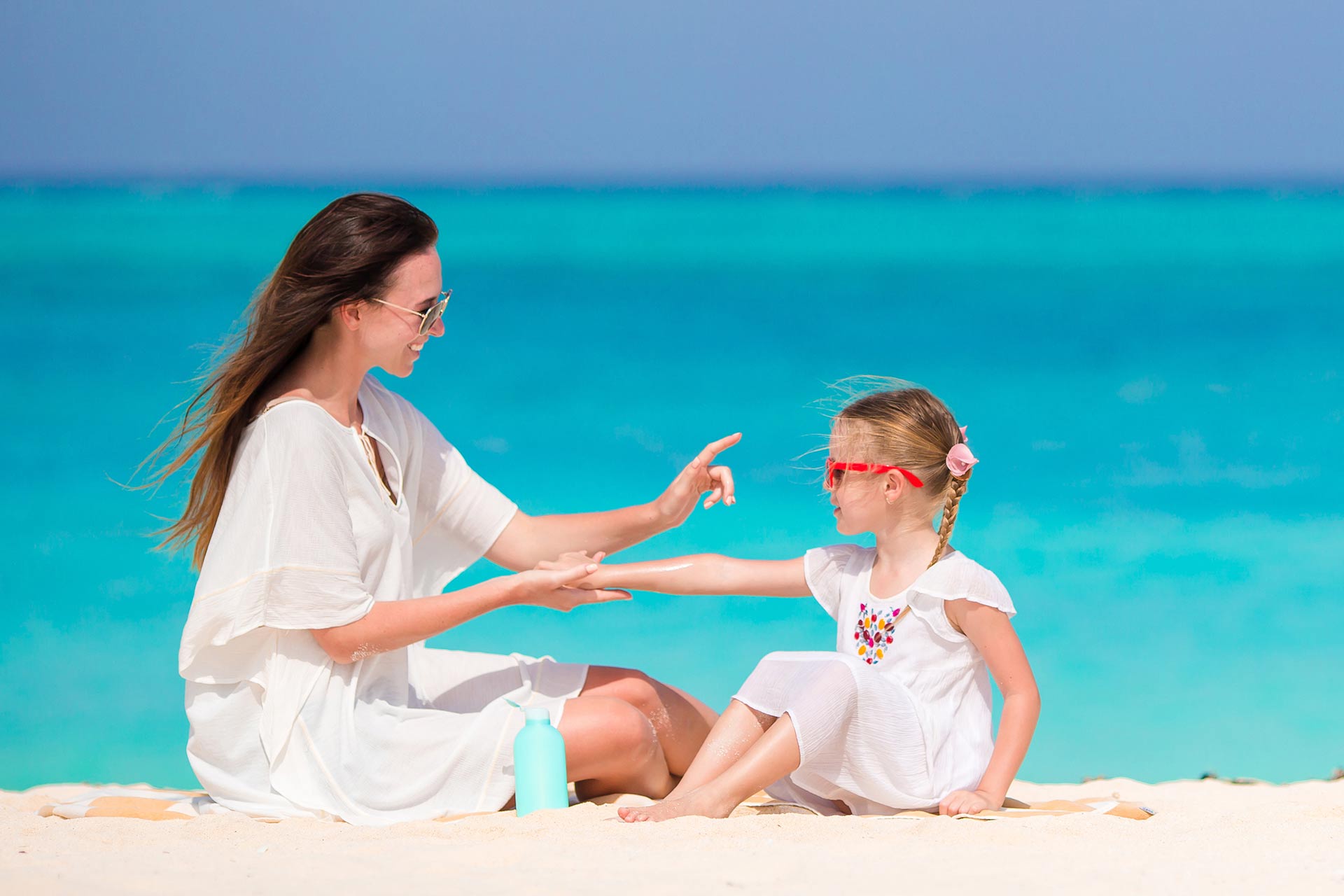 A mom applying sunscreen on her daughter.