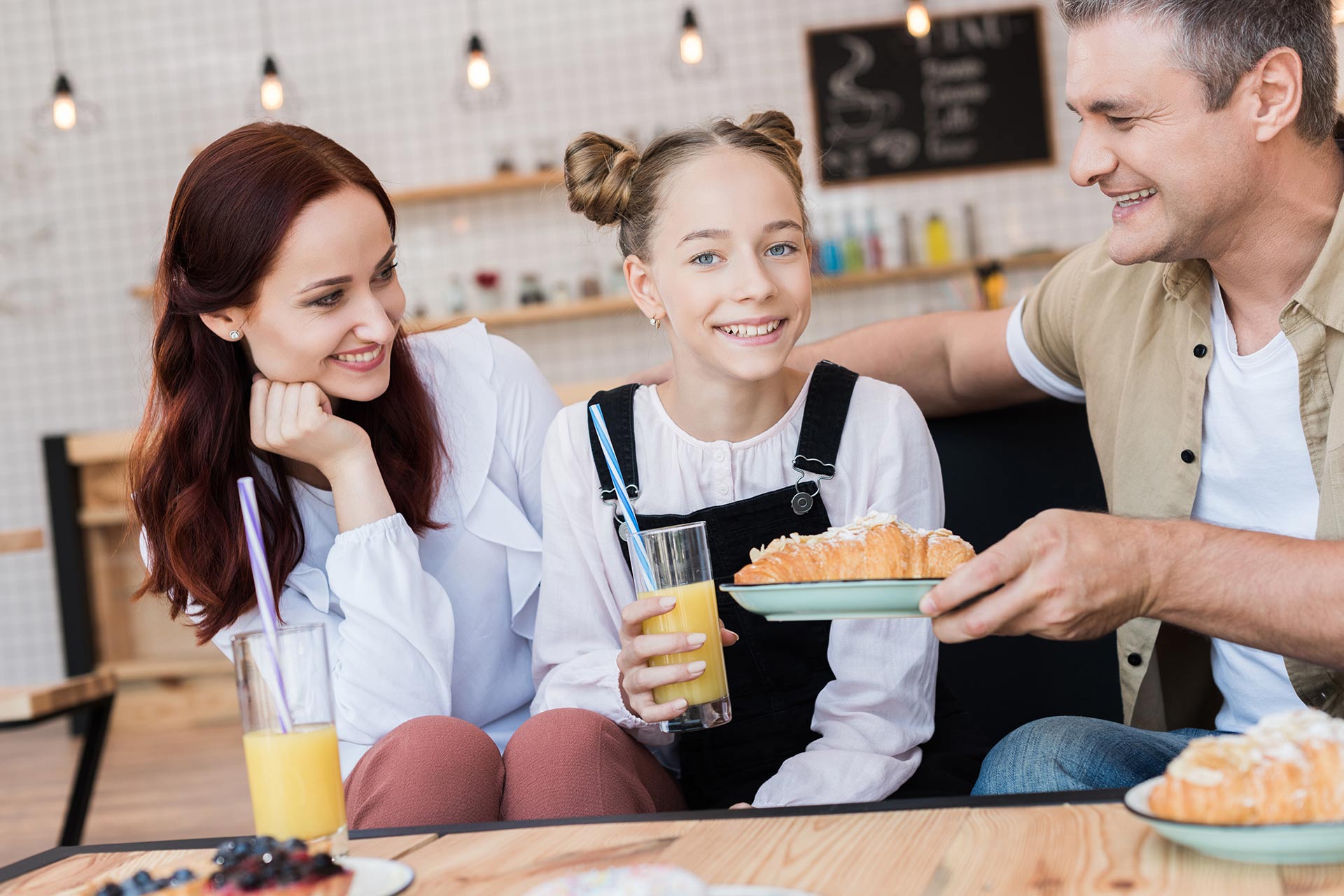 A family with desserts and orange juice in a cafe.