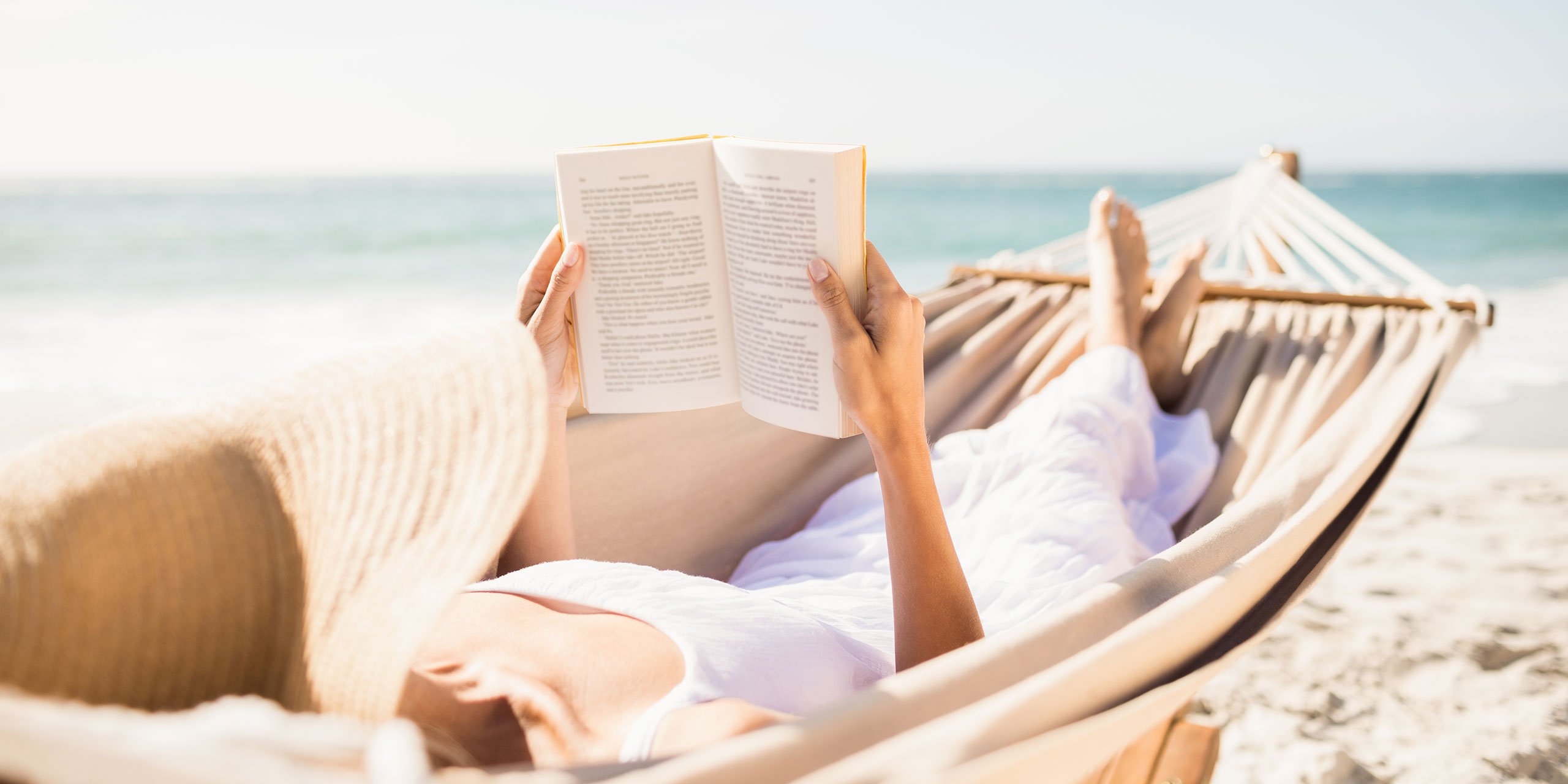 Woman Reading a Book on the Beach; Courtesy of wavebreakmedia/Shutterstock.com