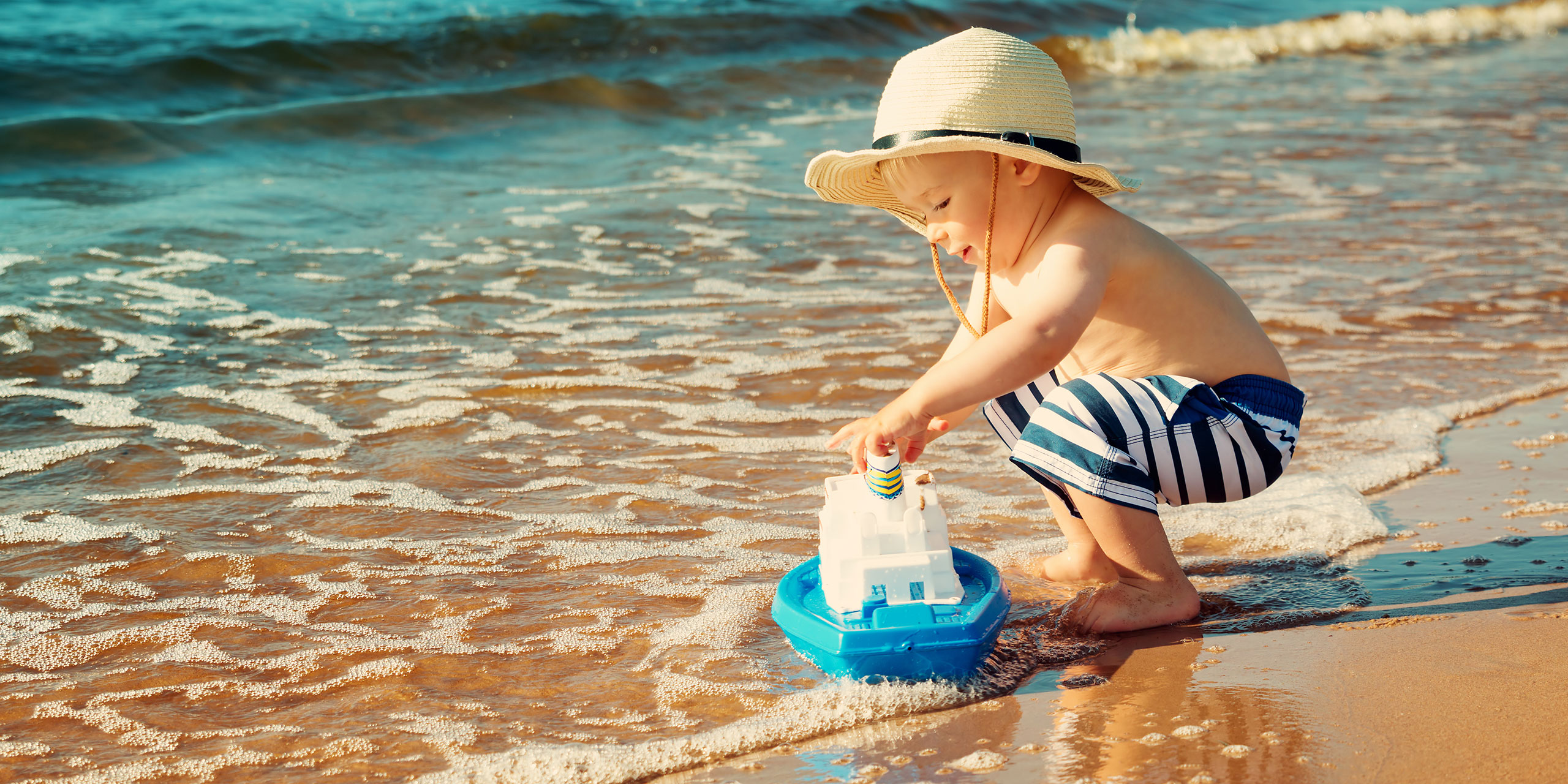 Boy Playing With Toy Boat on Beach; Courtesy of LeManna/Shutterstock.com