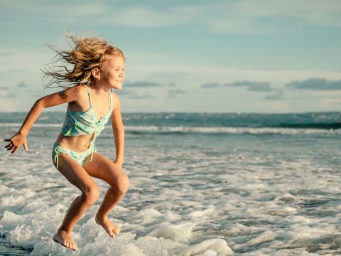 Little Girl Jumping in Ocean; Courtesy of altanaka/Shutterstock.com