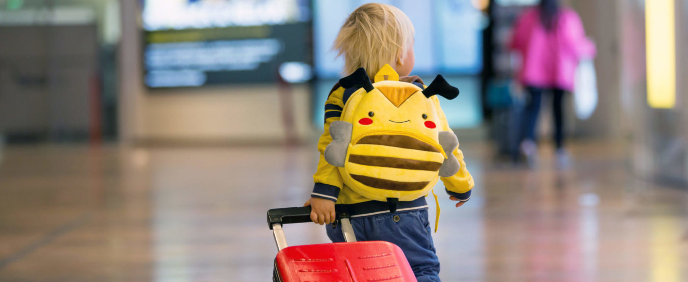 Child walking through airport with suitcase