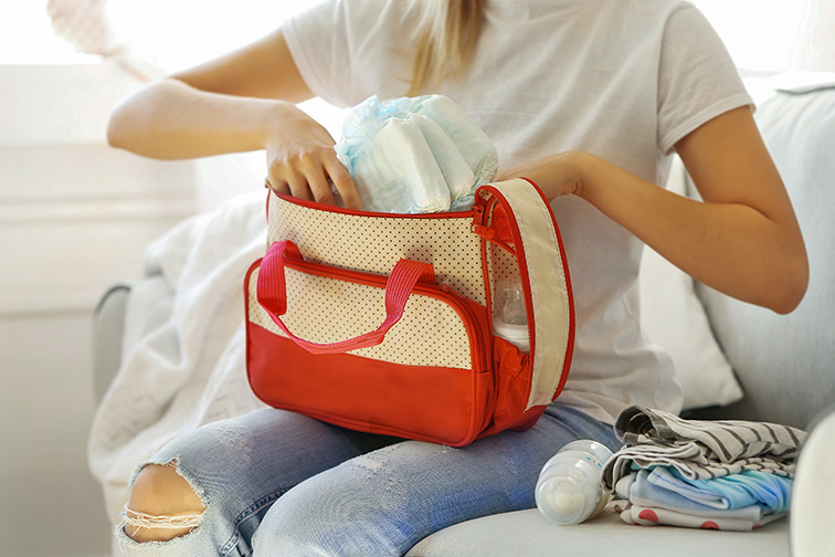 Woman packing her bag with diapers and wipes; Courtesy of Africa Studio/Shutterstock
