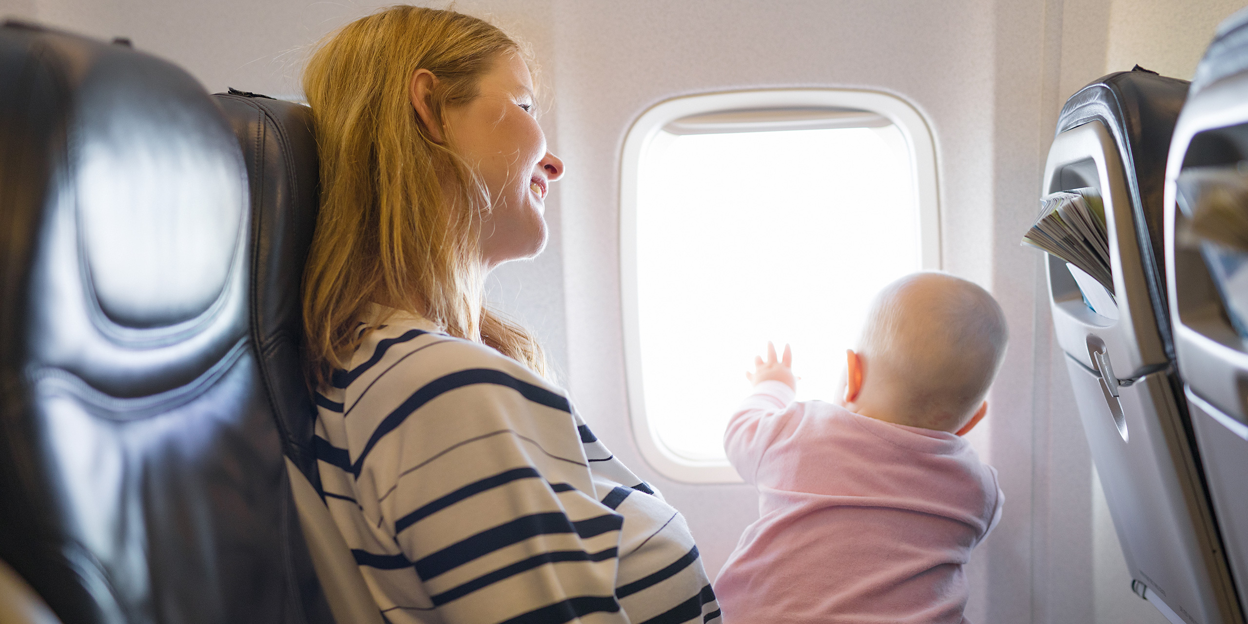 baby on moms lap in flight; Courtesy of Kaspars Grinvalds / Shutterstock