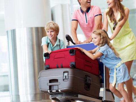 Family wheeling large suitcases in airport; Courtesy of AboutLife/Shutterstock
