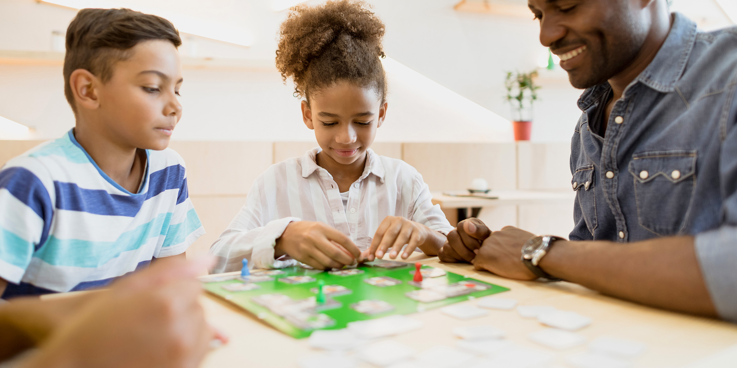 frican-american family playing board game in cafe; Courtesy of Lifield Studios/Shutterstock