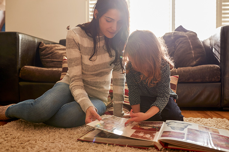 Mother And Daughter At Home Looking Through Photo Album; Courtesy of Monkey Business Images/Shutterstock