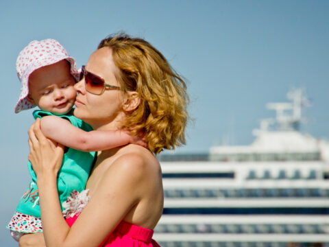 mom holds toddler in front of cruise ship; Courtesy Seleznev Oleg/Shutterstock