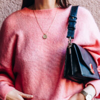 woman wearing pink sweater holding handbag