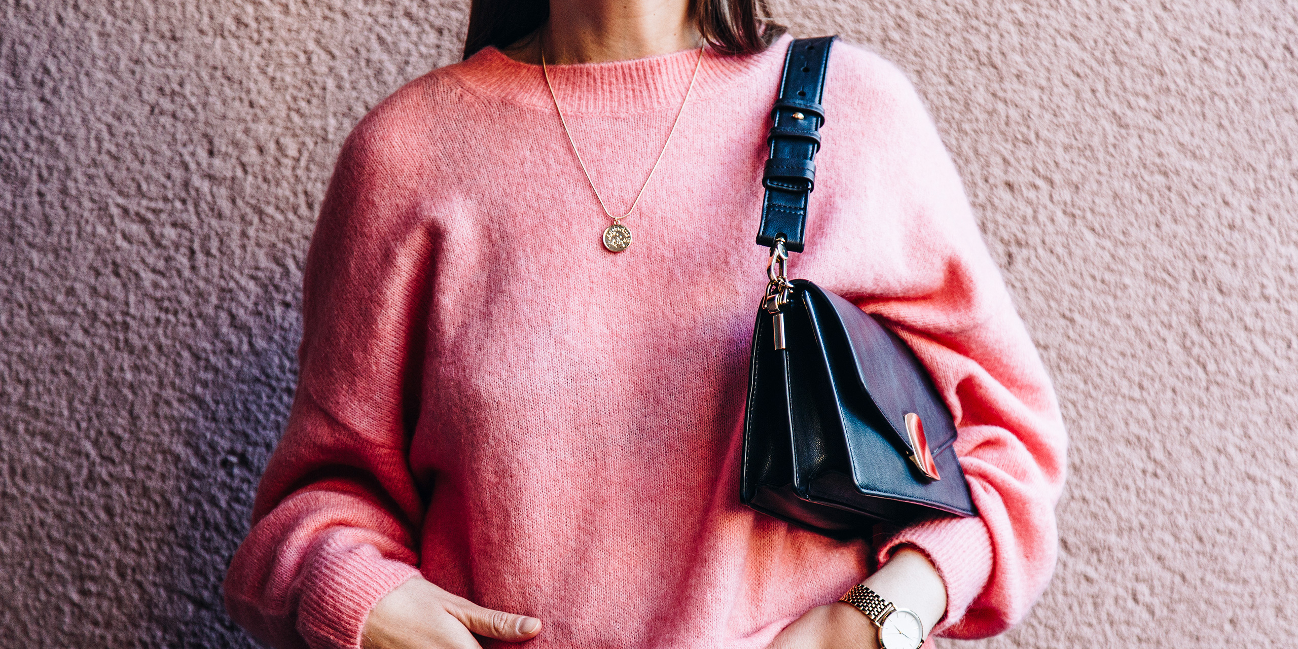 woman wearing pink sweater holding handbag