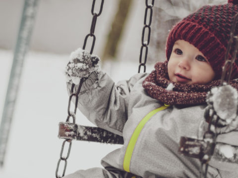 Toddler bundled in snow gear on a swing