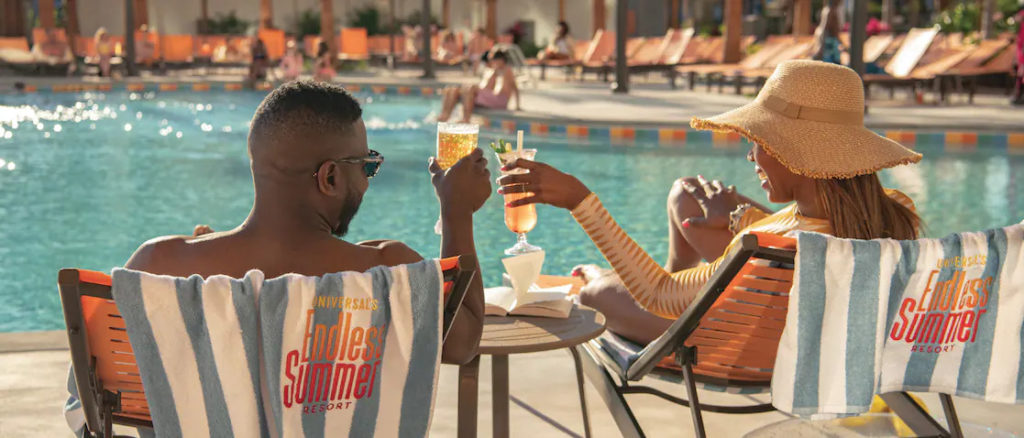 Two people drinking beside the pool at Endless Summer Resort Dockside Inn & Suites