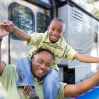 Son on his father's shoulders in front of their RV