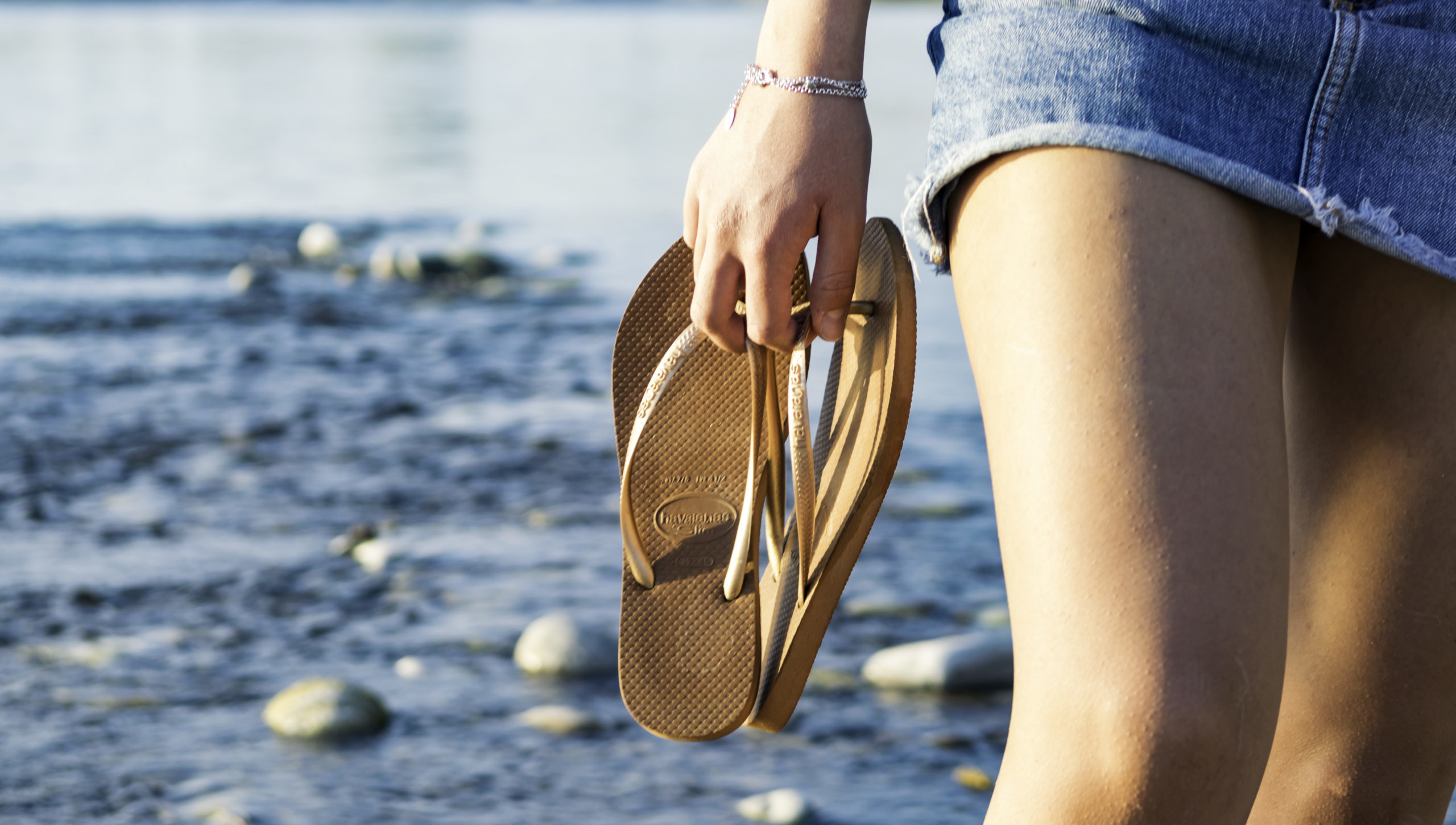 Woman holding flip flops on beach