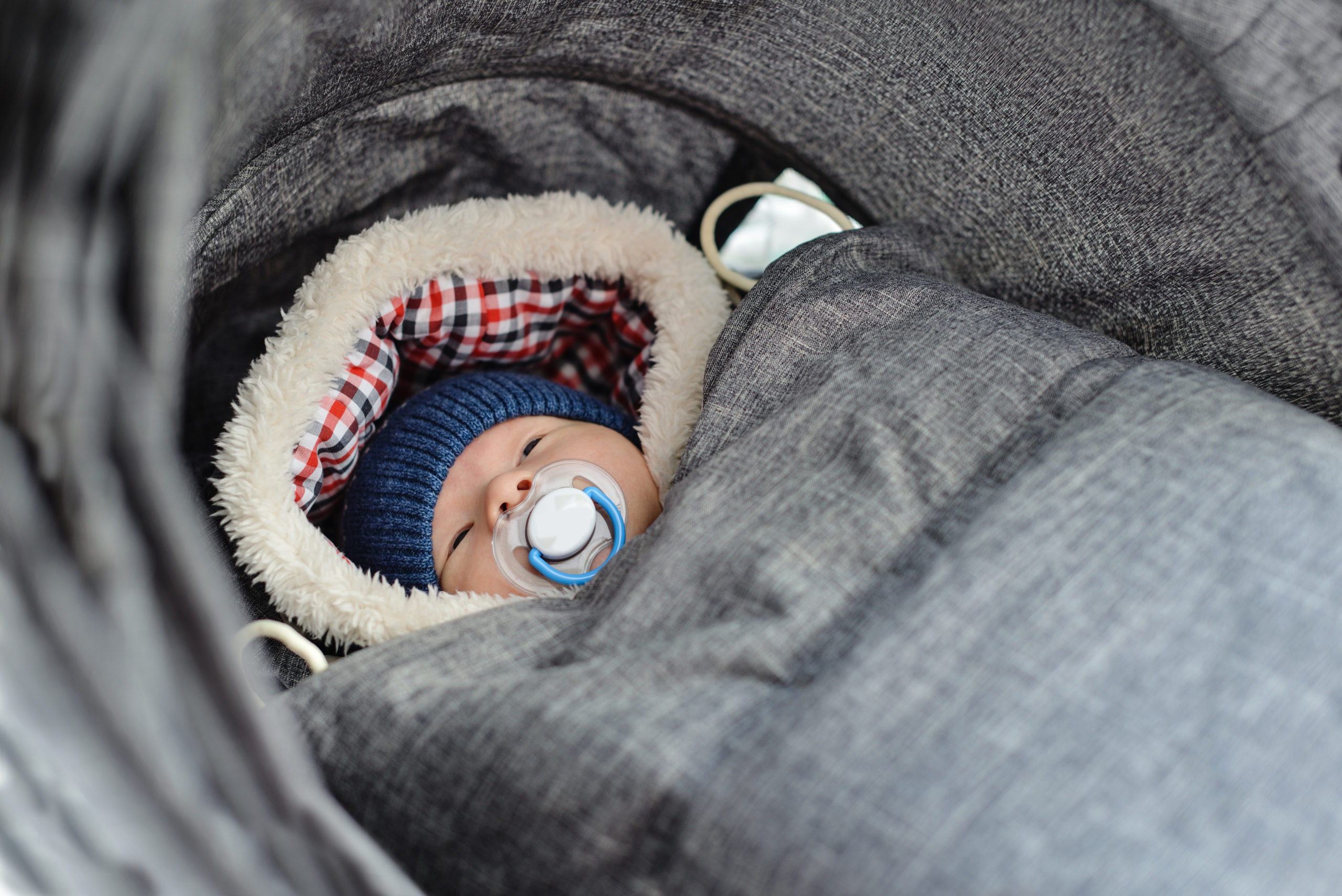Newborn baby bundled up for winter in a baby carrier