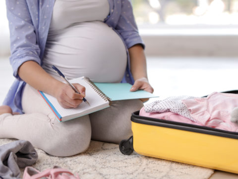 Pregnant woman packing a suitcase for the hospital