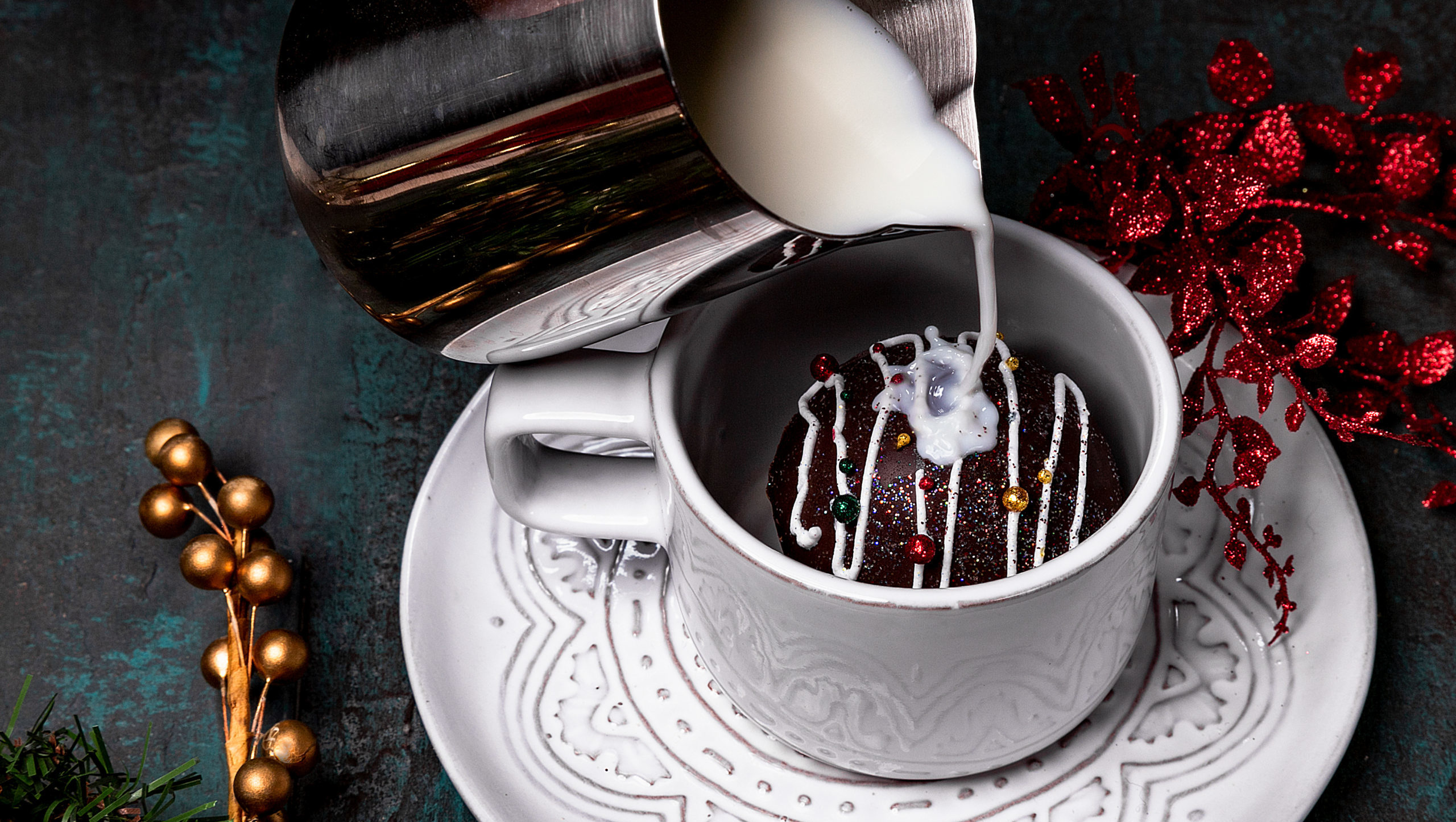 Close up of milk pouring over a hot chocolate bomb in a mug