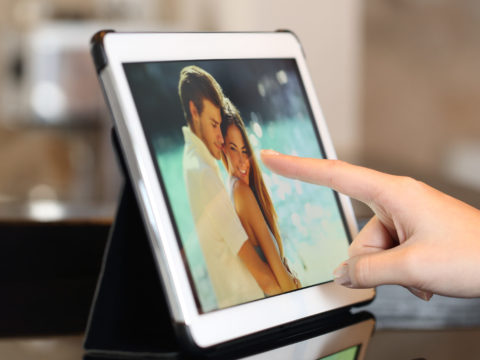 Close-up of a hand scrolling through images on a digital photo frame