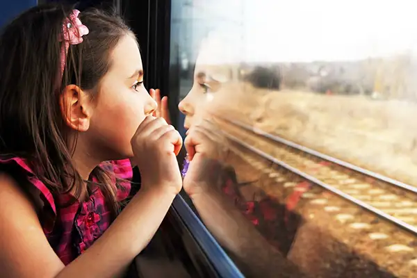 A little girl looking out the window of a train
