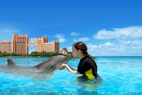 Young girl kissing a dolphin at Atlantis, Paradise Island in the Bahamas.