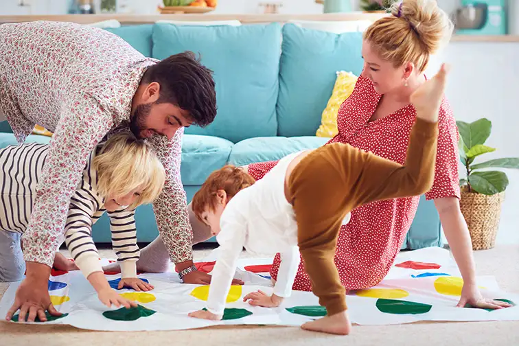 family having fun together, playing twister game at home; Courtesy of Olesia Bilkei/Shutterstock