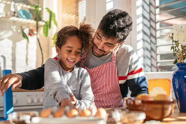 Smiling african american father and daughter baking in the kitchen; Courtesy of bbernard/Shutterstock