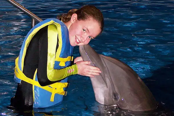 Little girl getting kissed by a dolphin.