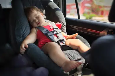 Baby sleeping on a road trip in a car seat.