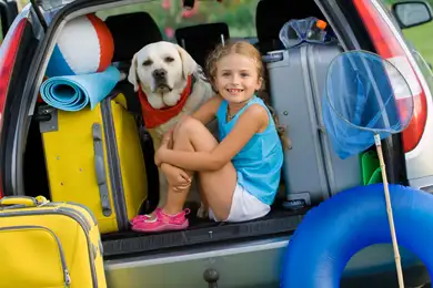 A little girl and her yellow labrador ready to embark on their next camping trip.