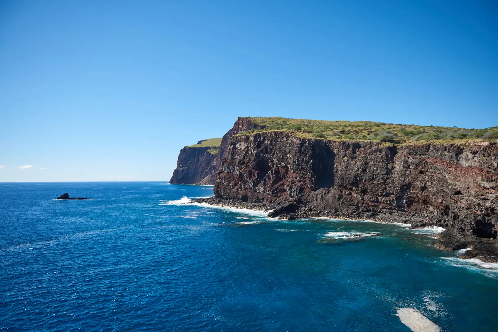 Photo of lanai island of Hawaii, water and cliffs, bright blue sky