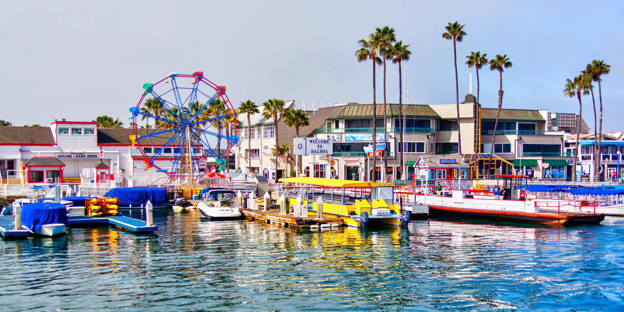 Popular pier at Balboa peninsula in Southern California with ferris wheel, tourist shops, restaurants and boats doting the harbor ferry terminal.; Courtesy of Ronnie Chua/Shutterstock