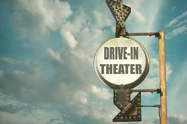 A vintage sign pointing to a drive-in theater; Courtesy of J.D.S / Shutterstock.com
