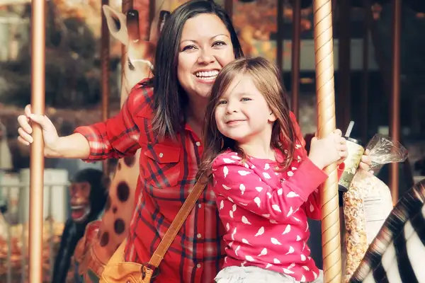 A mother and daughter riding a carousel together.