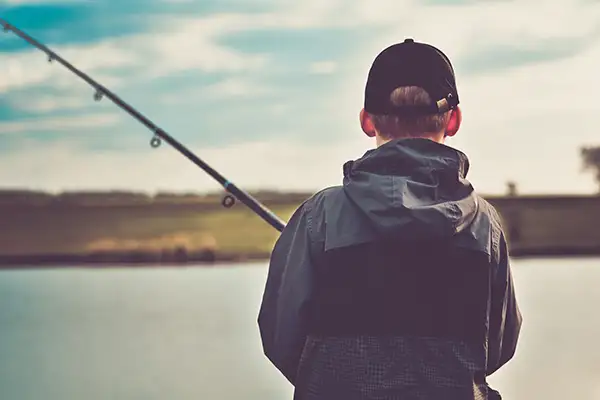 A boy with his fishing pole on the river.