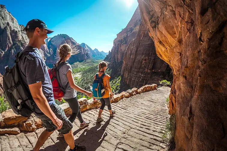 Group of hikers walking down the stairs and enjoying view of Zion National Park; Courtesy Dudarev Mikhail/Shutterstock